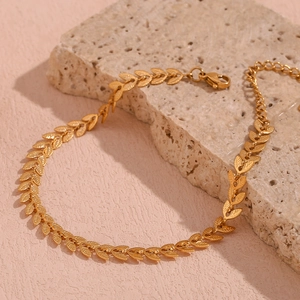 Macro detail of a 18K gold-plated leaf pattern bracelet on a natural stone surface