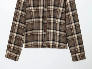 Detail of brown plaid shirt featuring high-quality woven fabric and neat buttoned hem