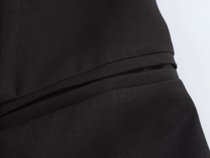 Detailed macro shot of high-quality black fabric texture and pocket stitching of blazer