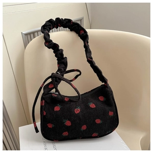 Detailed texture of black corduroy shoulder bag with red strawberry pattern and ruched strap