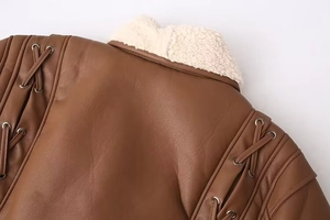 Détail de veste en cuir marron avec col en peau lainée et laçage à œillets aux épaules