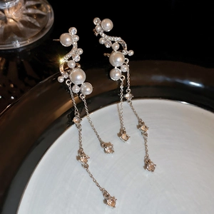 Détail de boucles d'oreilles à pampilles en perles et zircons sur une assiette en céramique