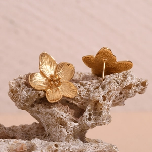 Macro detail of gold flower studs with petal texture on natural stone surface