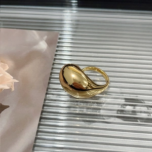 Detailed view of a gold-plated teardrop ring on a textured surface with soft lighting