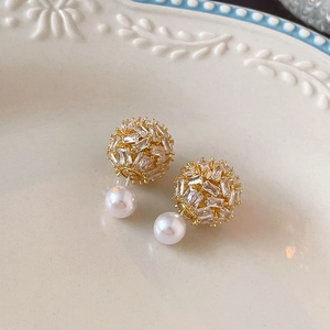 Detailed macro view of gold-plated pearl and cubic zirconia double-sided stud earrings