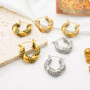 Macro view of twisted U-shaped earrings in gold and silver with inlaid cubic zirconia
