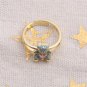 Macro shot of a gold teddy bear ring with blue pave crystals and a pink heart gem