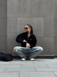 Streetwear style black zip-up sweatshirt paired with ripped jeans and sneakers
