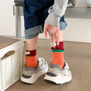 Close-up of color-block crew socks with striped design and woven letters label