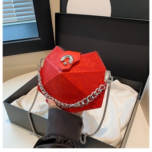 Close-up of red geometric crossbody bag with embossed patterns and silver chain in a box