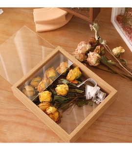 Detail of wooden shadow box frame featuring dried roses and decorative ribbon display