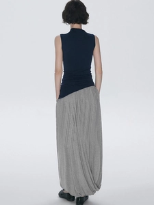 Detail shot of navy sleeveless top and grey pleated skirt showing elegant back drape