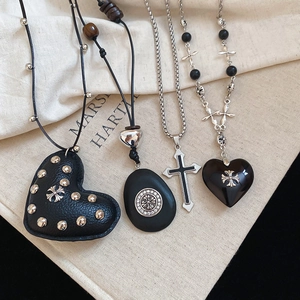 Detail of gothic cross and heart pendants in black leather and polished silver finish