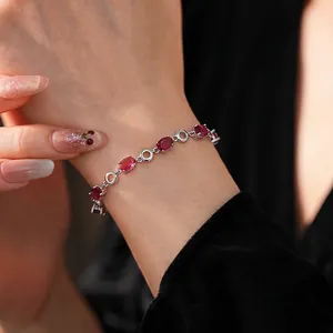 Elegant silver oval bracelet with deep red zircon gemstones on a female model wrist