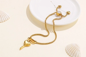 Détail du pendentif clé en forme de cœur doré sur une chaîne en acier titane réglable