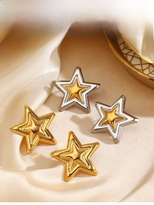 Detailed view of layered star stud earrings in gold and silver on champagne satin
