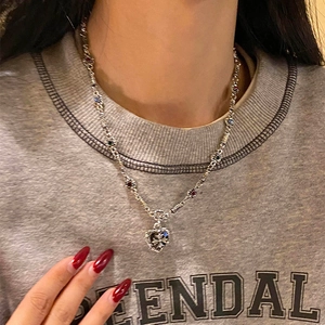 Close-up of gothic heart cross necklace with colorful gems on a female model
