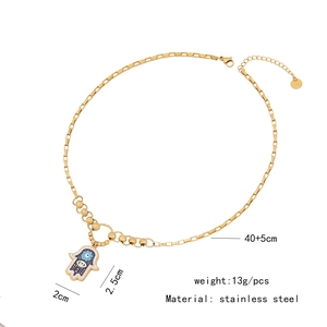 Detail of gold Hamsa hand necklace with blue evil eye pendant and zircon stones