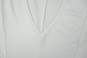 Close-up of a white V-neck short-sleeve dress showing fine stitching and soft fabric texture