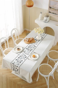 Close-up of geometric floral embroidery and tassel fringe on a cream waterproof tablecloth