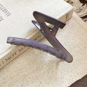 Detail of a purple translucent geometric shark hair claw clip on a minimalist background