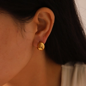 Gros plan d'une boucle d'oreille clip en acier inoxydable doré poli portée à l'oreille