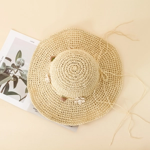 Gros plan sur un chapeau de paille à large bord avec fleurs en tissu et rubans