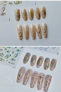 Détail d'autocollants holographiques dorés en forme de cœur sur faux ongles roses