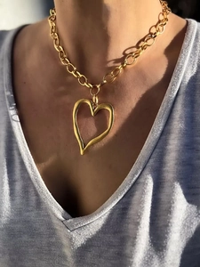 Gros plan d'un collier chaîne dorée avec un grand pendentif cœur martelé sur un mannequin