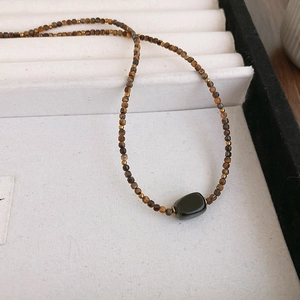 Macro shot of brown beaded necklace with a polished black oval natural stone pendant