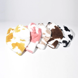 Detailed view of various plush cow print bucket hats in multiple colors for winter