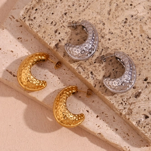 Vue détaillée de boucles d'oreilles C dorées et argentées avec texture martelée sur pierre