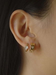 Gros plan de boucles d'oreilles cœur en plaqué or 18 carats portées par un modèle