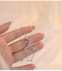 Detailed close-up of a silver crescent moon and star pendant on a dainty bracelet chain