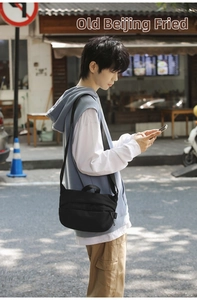 Street style shot of a black minimalist nylon crossbody bag with adjustable wide strap