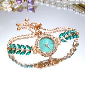 Detailed view of luxury gold quartz watch with green leaf gems and crystal bezel