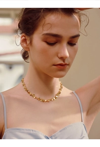 Close-up of golden sequin heart choker necklace worn by a model in soft sunlight