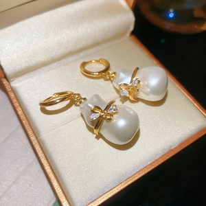 Détail macro de boucles d'oreilles perles baroques plaquées or 18 carats avec nœud diamant