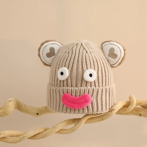 Vue détaillée du bonnet en maille beige avec oreilles d'ours et lèvres de dessin animé
