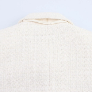 Close-up of beige tweed jacket collar and back showing refined woven fabric texture