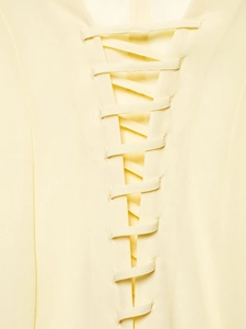 Détail macro du laçage ajustable sur un chemisier en mousseline de soie jaune pâle