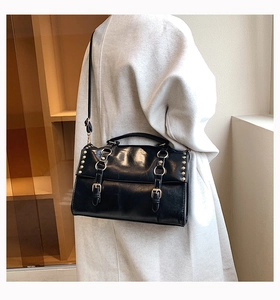British style black oil wax leather shoulder bag with rivets shown on a model