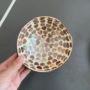 Close-up of coconut shell bowl with heart-shaped iridescent shell inlay and mosaic texture