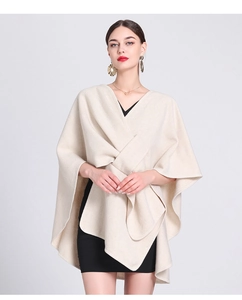 Detail of loose-fit beige knitted shawl poncho featuring a soft asymmetric fashion design