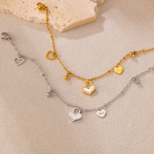 Elegante gold- und silberne Herz-Charm-Armbänder auf einem sandigen Hintergrund