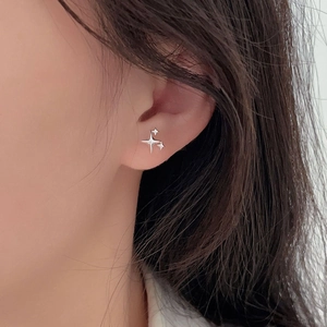 Close-up of minimalist silver star stud earrings worn by a model for size perspective