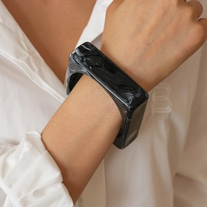 Detail of square black marble texture acrylic bangle on model with white shirt