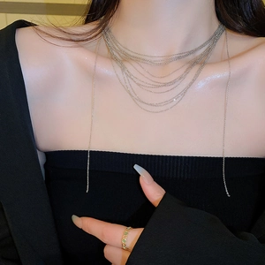Dettaglio di una collana a frange d'argento multistrato su una modella in nero