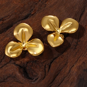 Minimalist gold three-petal flower earrings displayed on a dark rustic wooden surface