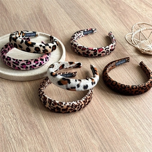 Padded leopard print velvet headbands in multiple colors on a textured surface